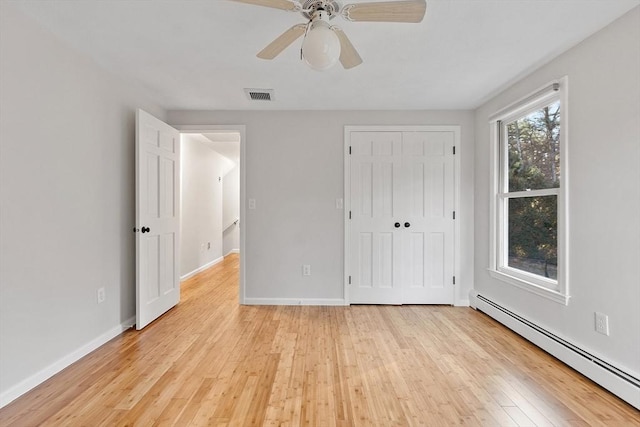 unfurnished bedroom with ceiling fan, a closet, a baseboard radiator, and light hardwood / wood-style floors