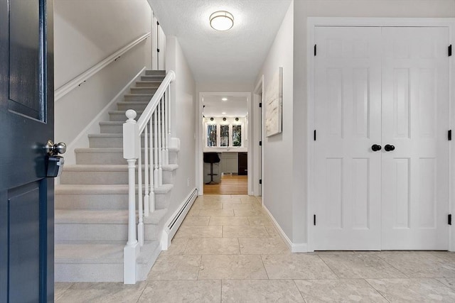 tiled entrance foyer featuring a textured ceiling and a baseboard heating unit