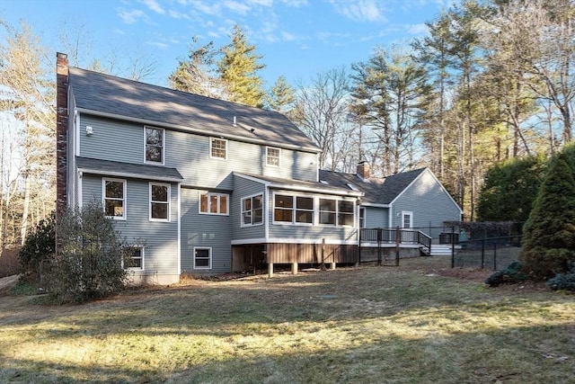 rear view of property with a yard, a deck, and a sunroom