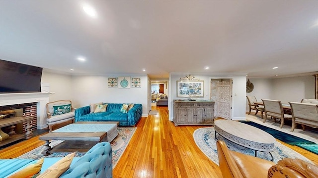 living room featuring ornamental molding, a fireplace, and light hardwood / wood-style flooring