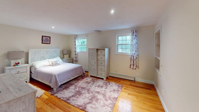 bedroom with light hardwood / wood-style floors and a baseboard radiator