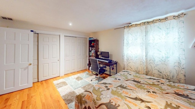 unfurnished bedroom with multiple closets and light wood-type flooring