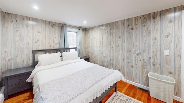 bedroom with radiator, wooden walls, and hardwood / wood-style floors