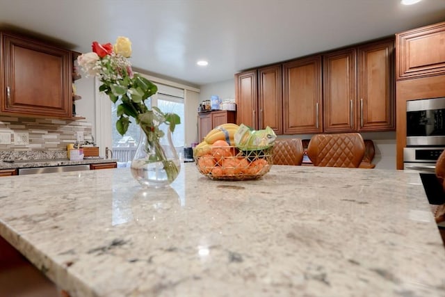 kitchen featuring decorative backsplash, dishwasher, and light stone counters