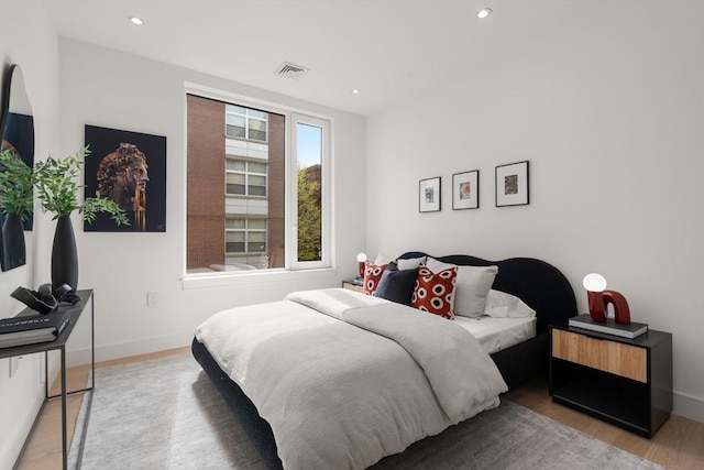 bedroom with baseboards, wood finished floors, visible vents, and recessed lighting