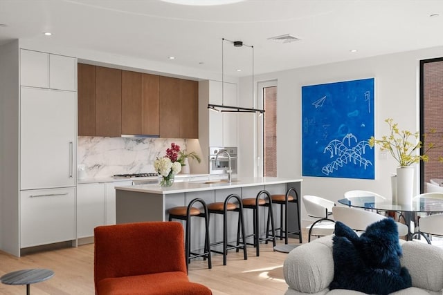 kitchen featuring a sink, brown cabinetry, light wood-style floors, modern cabinets, and light countertops