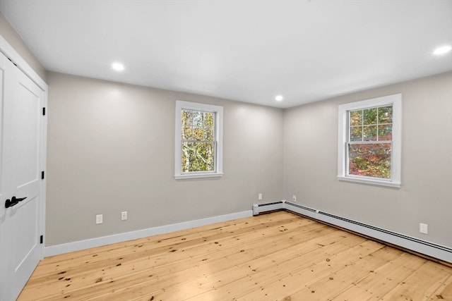 unfurnished room with baseboard heating, light hardwood / wood-style flooring, and a wealth of natural light