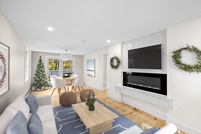 living room featuring a fireplace, a notable chandelier, and wood-type flooring