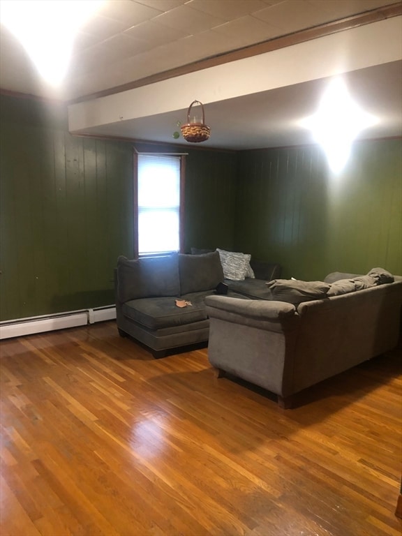 living room featuring wooden walls, hardwood / wood-style floors, and a baseboard radiator