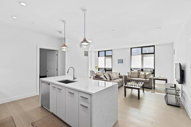 kitchen featuring stainless steel dishwasher, pendant lighting, sink, white cabinets, and a kitchen island with sink