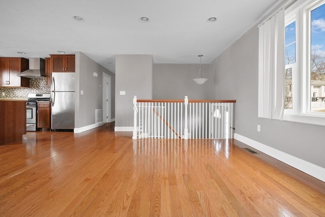 interior space with baseboards, visible vents, and light wood finished floors