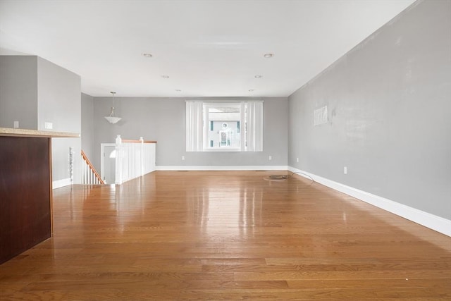 unfurnished living room featuring wood finished floors and baseboards