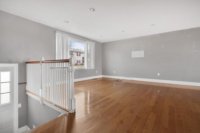 empty room with baseboards, wood finished floors, and recessed lighting