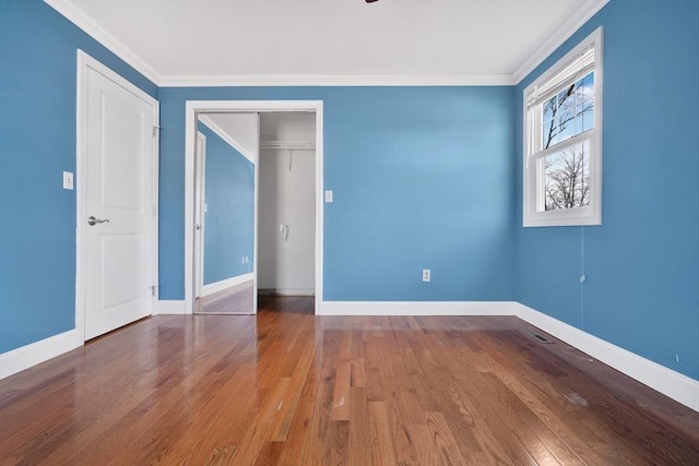 unfurnished bedroom featuring a closet, crown molding, baseboards, and wood finished floors