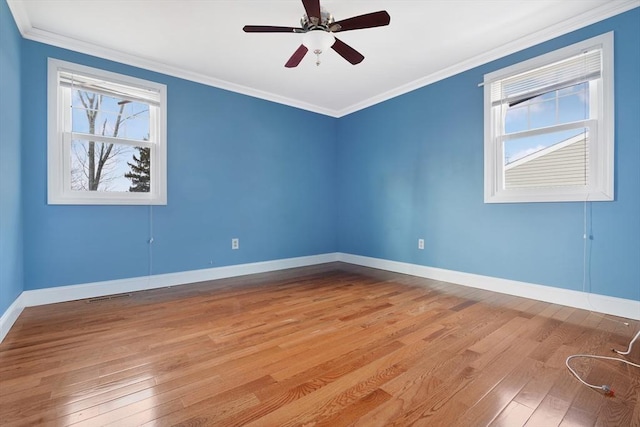 empty room featuring baseboards, ornamental molding, and light wood-style floors