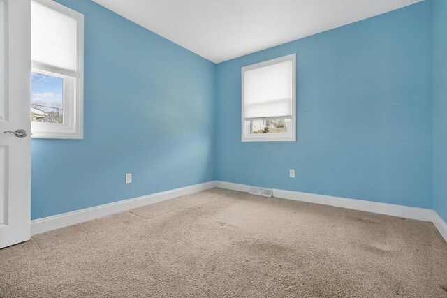 spare room featuring carpet, visible vents, and baseboards