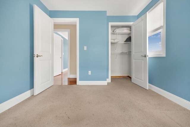 unfurnished bedroom with light carpet, a closet, and baseboards