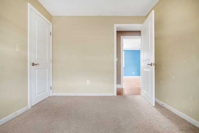 spare room with baseboards and light colored carpet