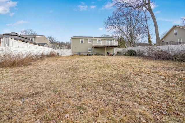 back of house with a fenced backyard, a lawn, and a wooden deck