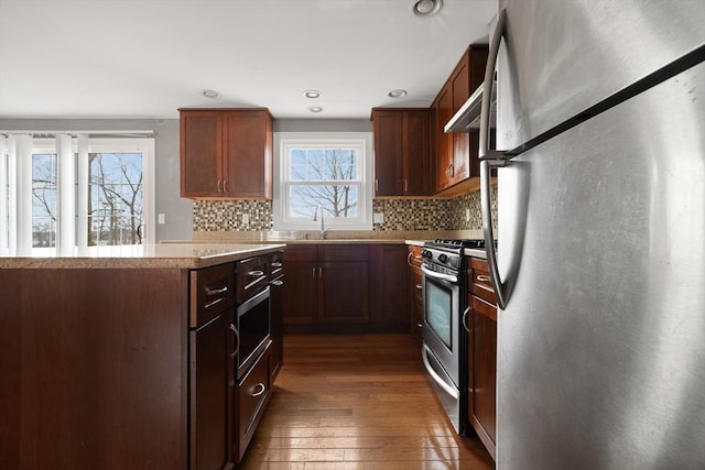 kitchen with stainless steel appliances, a healthy amount of sunlight, light countertops, and dark wood finished floors