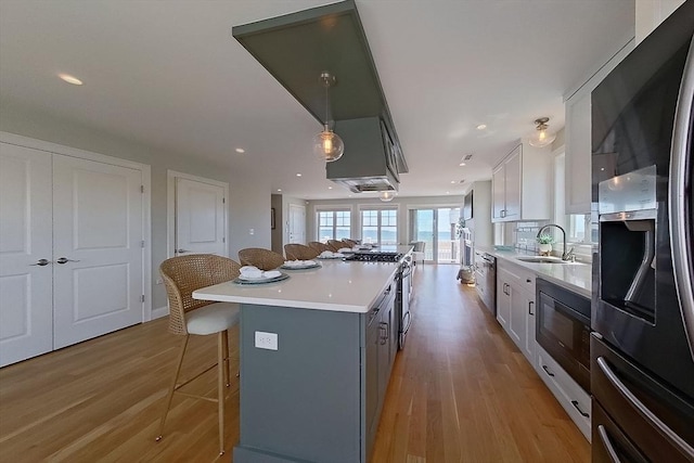 1089 Winthrop Ave Unit A, Revere, MA 02151 - kitchen featuring stainless steel appliances, a breakfast bar, light wood-style floors, a kitchen island, and white cabinetry