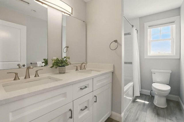1089 Winthrop Ave Unit A, Revere, MA 02151 - bathroom featuring toilet, double vanity, baseboards, wood finished floors, and shower / bath combo with shower curtain