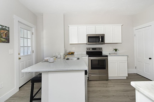 29 Maple St Unit 2, Uxbridge, MA 01569 - kitchen featuring appliances with stainless steel finishes, light wood-type flooring, white cabinets, and a breakfast bar area