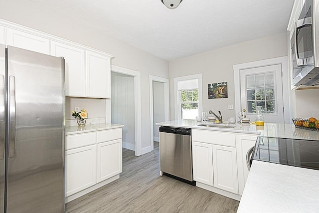 29 Maple St Unit 2, Uxbridge, MA 01569 - kitchen with appliances with stainless steel finishes, light countertops, light wood-style flooring, white cabinets, and a peninsula
