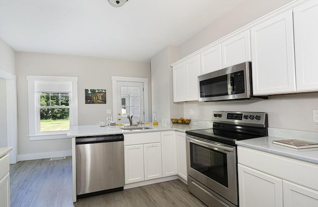 29 Maple St Unit 2, Uxbridge, MA 01569 - kitchen with appliances with stainless steel finishes, a peninsula, light wood-style flooring, light countertops, and white cabinets
