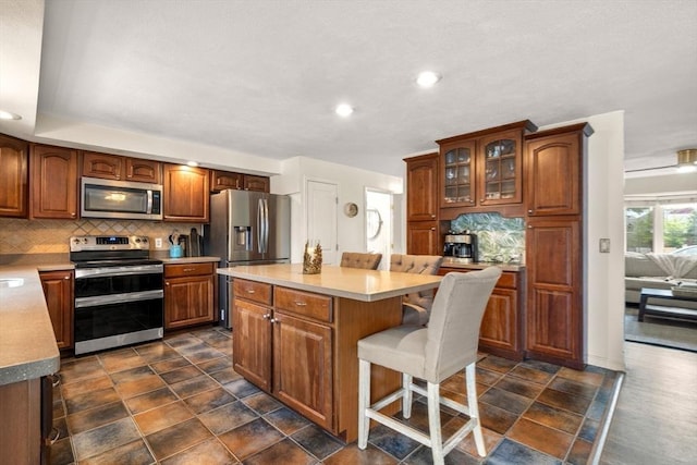 40 Fowler Ave, Revere, MA 02151 - kitchen featuring appliances with stainless steel finishes, decorative backsplash, a kitchen breakfast bar, a kitchen island, and recessed lighting