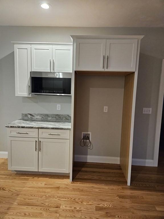 kitchen featuring light hardwood / wood-style floors, light stone countertops, and white cabinetry