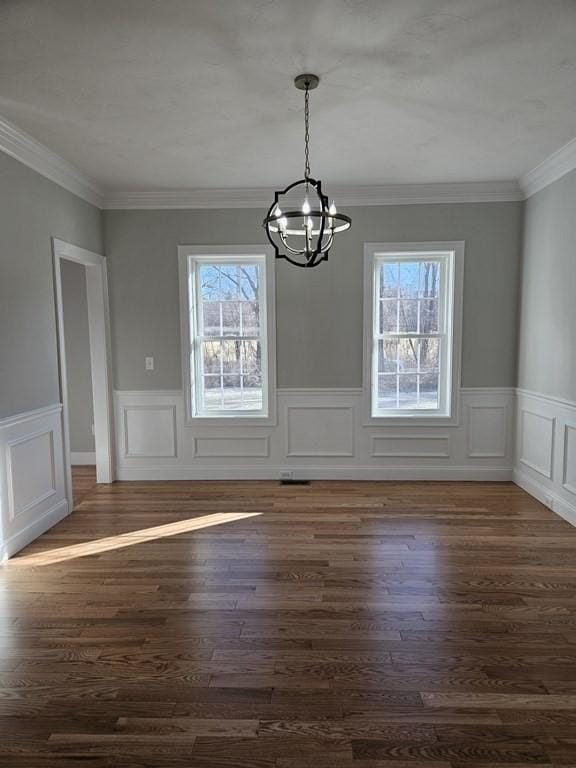 unfurnished dining area with dark wood-type flooring, a notable chandelier, and crown molding