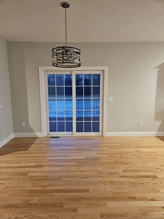 unfurnished dining area with a notable chandelier and light hardwood / wood-style flooring