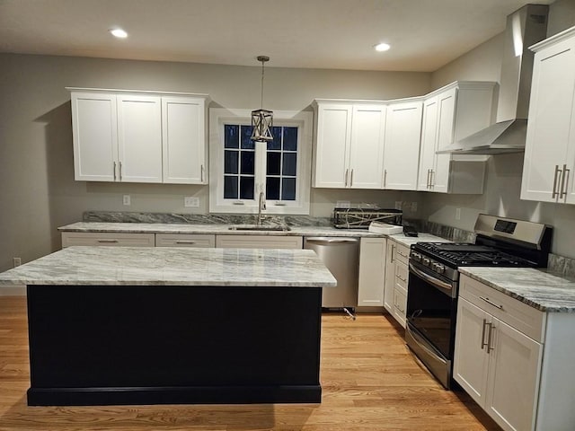 kitchen featuring white cabinets, wall chimney exhaust hood, sink, and stainless steel appliances