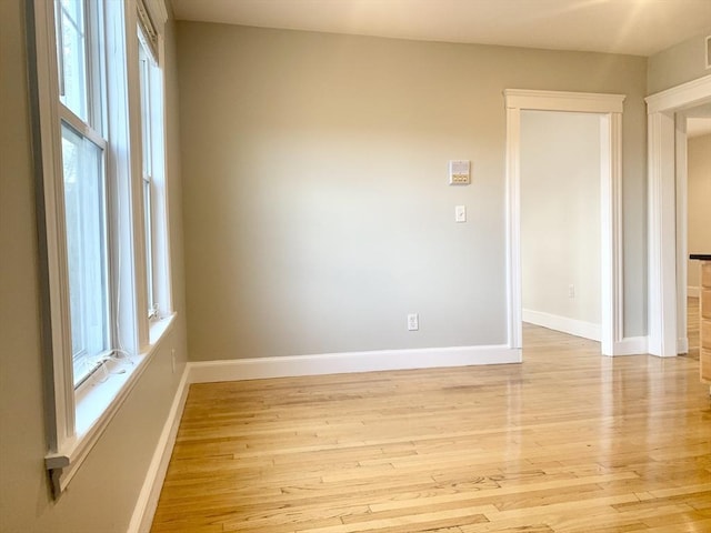 spare room featuring baseboards and light wood finished floors