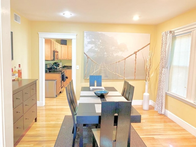 dining area with visible vents, light wood-type flooring, and baseboards