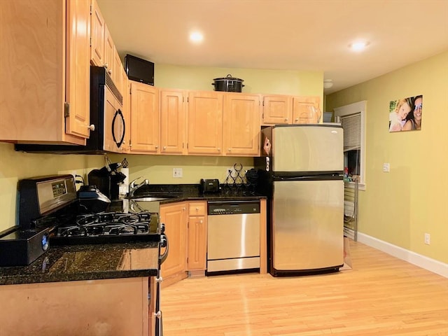 kitchen featuring light wood-type flooring, light brown cabinets, a sink, stainless steel appliances, and baseboards