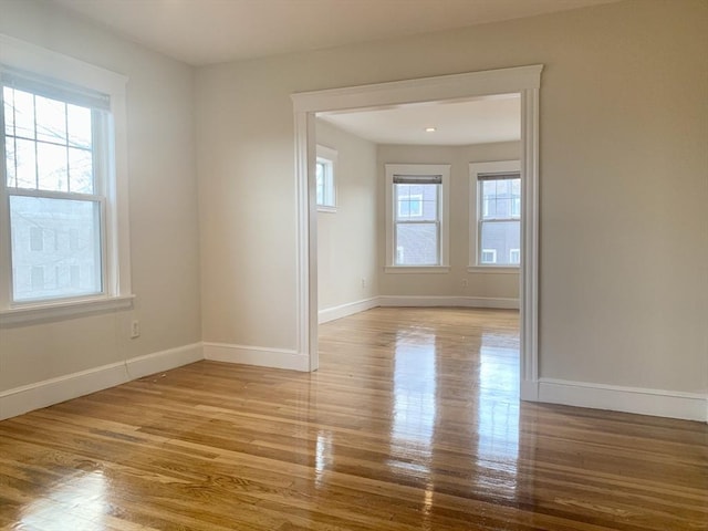 empty room featuring plenty of natural light, baseboards, and wood finished floors