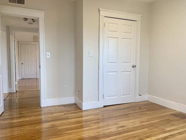 unfurnished bedroom featuring visible vents, baseboards, a closet, and light wood finished floors