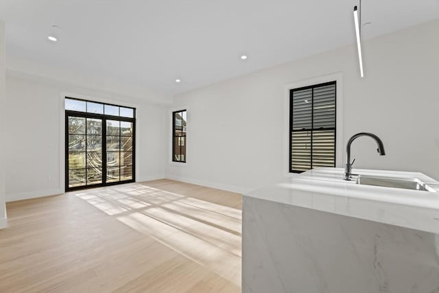 unfurnished living room with light hardwood / wood-style floors and sink