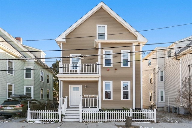 view of front of property featuring covered porch, a fenced front yard, and a balcony