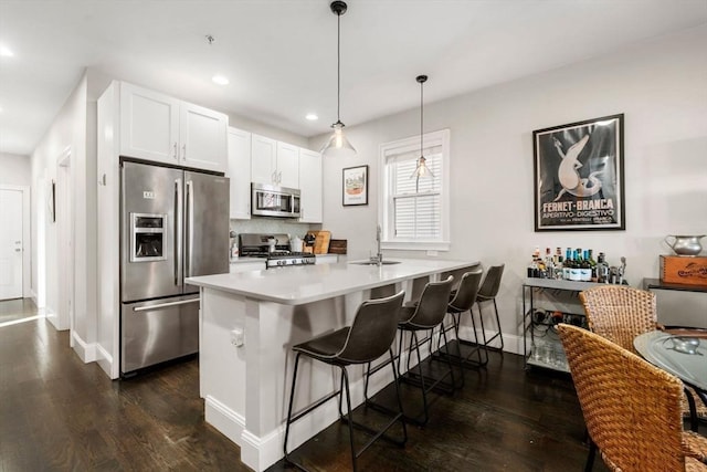 kitchen with stainless steel appliances, dark wood finished floors, a sink, and a kitchen bar