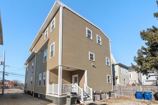 rear view of property featuring covered porch, central AC, and fence