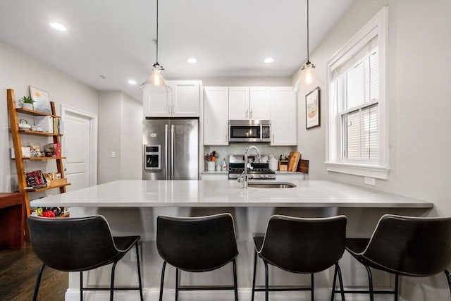 kitchen featuring white cabinets, dark wood-style flooring, a peninsula, stainless steel appliances, and light countertops