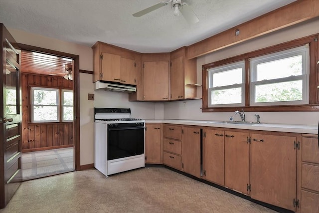 kitchen with a textured ceiling, white range, ceiling fan, sink, and wood walls