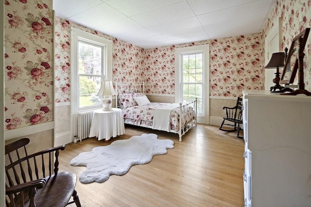 38 Spring St, Somerville, MA 02143 - bedroom with wallpapered walls, radiator heating unit, wainscoting, and light wood finished floors