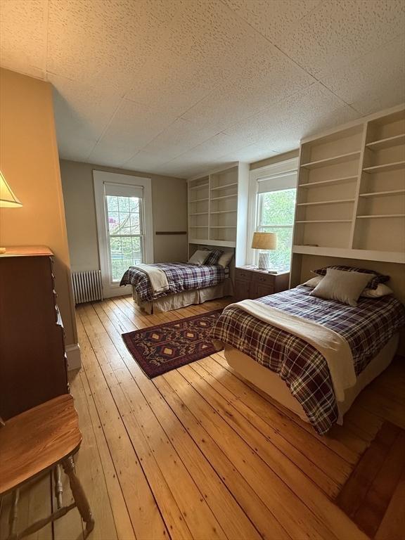 38 Spring St, Somerville, MA 02143 - bedroom featuring radiator, a textured ceiling, and light wood-style flooring