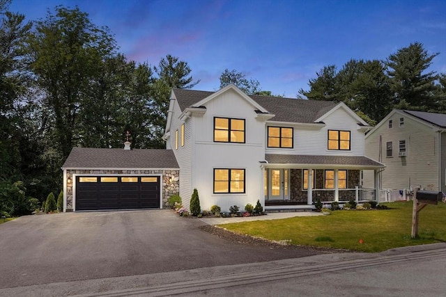 14 Corcoran Rd, Burlington, MA 01803 - view of front of property featuring stone siding, asphalt driveway, a front yard, an attached garage, and covered porch