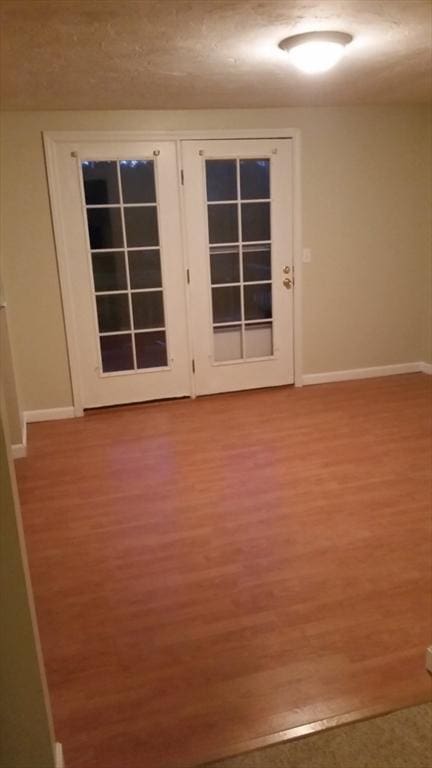 spare room with hardwood / wood-style flooring and french doors