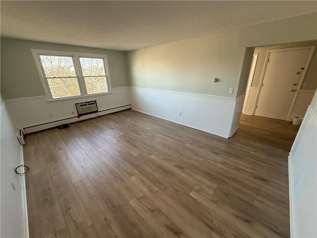 unfurnished room featuring a baseboard heating unit, hardwood / wood-style floors, and a textured ceiling